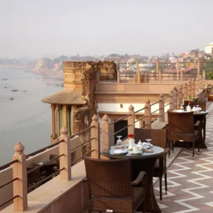 Historic stone palace building situated right on the edge of the Ganges River, with boats docked nearby, in Varanasi.
