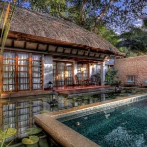 Outdoor view of a private plunge pool next to a luxurious villa, surrounded by tropical greenery at Evolve Back Coorg.